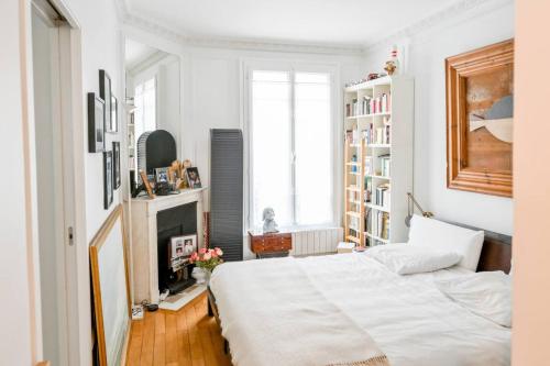 une chambre blanche avec un lit et une cheminée dans l'établissement Bel appartement pour 2 personnes by Weekome, à Paris