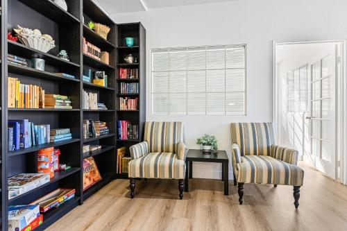 two chairs and a table in a library with bookshelves at Walk to Beach Pool Hot Tub Private Patio Parking Seabreeze Retreat in Dana Point