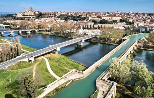 un pont sur une rivière avec une ville en arrière-plan dans l'établissement Charmand Studio dans le coeur historique de Beziers, à Béziers