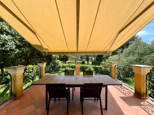 a wooden table and chairs under a large umbrella on a patio at Appartamento Golf in Lerici