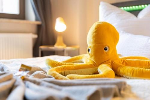 a stuffed animal is sitting on a bed at Macabu Apartment Marie in Zwickau