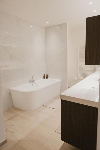 a white bathroom with a tub and a sink at Blue Bird Residence in Antwerp