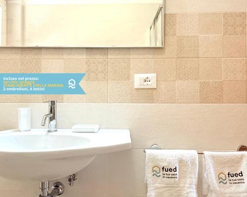 a bathroom with a sink and a mirror and towels at VIVA2 - Numana, quadrilocale in villa con piscina in Numana