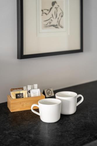 two white cups sitting on a table with a picture at Przystań Stegna in Stegna