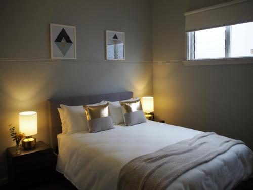 a bedroom with a large white bed with two lamps at City Quarters on Brewer in Perth