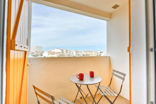 d'une petite table et de chaises sur un balcon avec fenêtre. dans l'établissement Les Mouettes - Appartement bord de mer, à La Parée Preneau