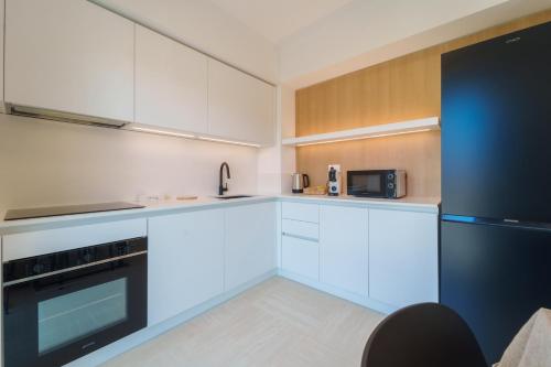 a kitchen with white cabinets and a black refrigerator at Mavi Apartments in Porto Azzurro