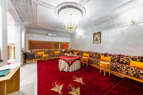 a dining room with a table and chairs on a red carpet at Riad Les Champs De Fès in Fès