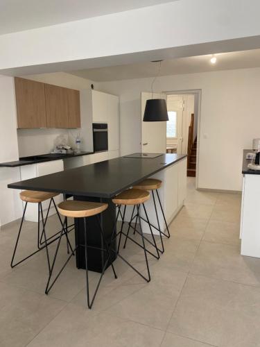 une cuisine avec un comptoir noir et des tabourets dans l'établissement Maison de vacances Wim & Chill, à Wimereux