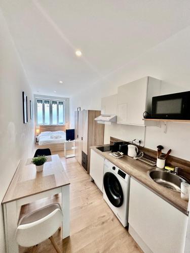 une cuisine blanche avec un évier et une cuisinière dans l'établissement L'Alsacien - Villeurbanne - Métro A et B, à Villeurbanne