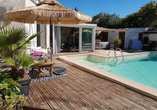 - une piscine avec un parasol et une terrasse en bois dans l'établissement Tropical Spirit House, à Marignane