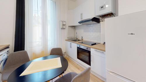 une cuisine avec une table, des chaises et un réfrigérateur dans l'établissement F3- Rue Amiral Courbet, au Havre