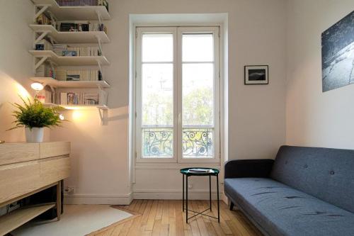 un salon avec un canapé et une fenêtre dans l'établissement Cosy apartment in the 11th arrondissement, à Paris