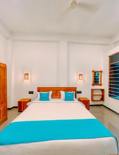 a bedroom with a large white bed with blue pillows at Peak Bay Resort in Arugam Bay