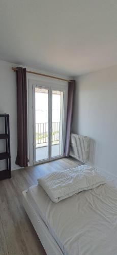 Cette chambre comprend un lit blanc et une grande fenêtre. dans l'établissement Chez Bibi, à Saint-Georges-de-Didonne