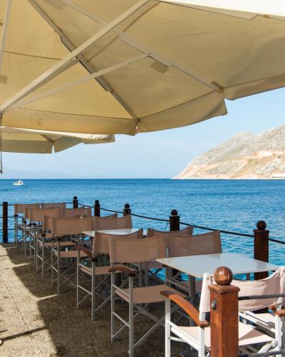 a row of tables and chairs next to the ocean at Nireus Hotel in Symi