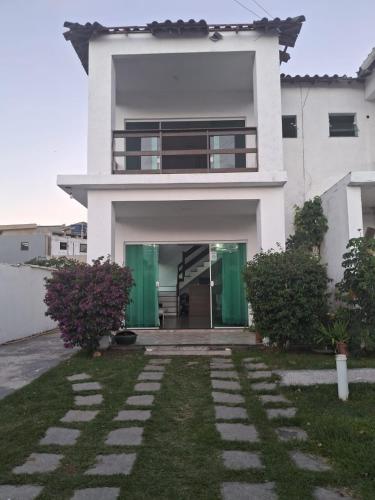 a white house with green doors and a yard at Pousada Ebenézer, Foguete in Cabo Frio