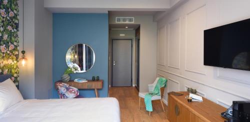 a living room with a bed and a tv at The Oscar Olympic Hotel in Thessaloniki