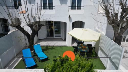 a house with a patio with chairs and an umbrella at #267 Cozy Villa Casablanca in Albufeira