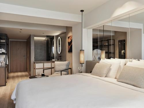 a bedroom with a large white bed and a kitchen at NIKO Seaside Resort MGallery in Agios Nikolaos