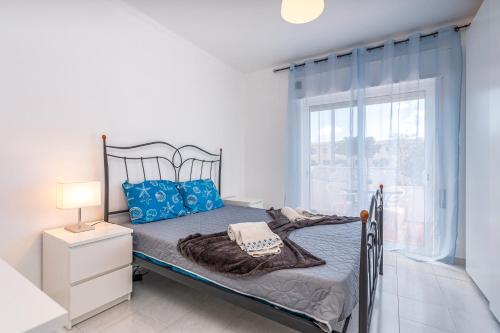 ein Schlafzimmer mit einem Bett mit blauen Kissen und einem Fenster in der Unterkunft Isabel apartment in Carvoeiro