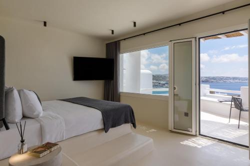 a bedroom with a bed and a view of the ocean at Rocabella Mykonos Hotel in Agios Stefanos