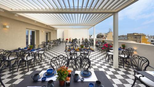 a patio with tables and chairs on a balcony at The Oscar Olympic Hotel in Thessaloniki