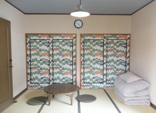 a room with a table and a clock on the wall at Guest House coco-Rin in Hamamatsu