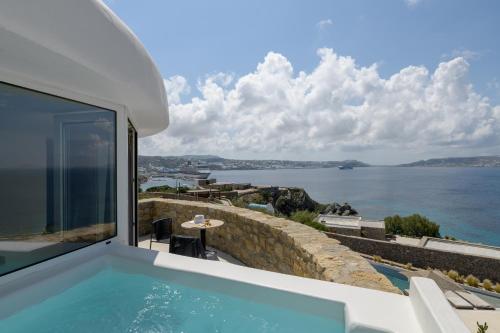 a house with a swimming pool with a view of the water at Rocabella Mykonos Hotel in Agios Stefanos
