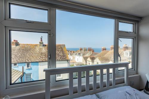 a bedroom with large windows and a bed with a crib at Dog Friendly Cosy Coastal Cottage with Sea Views in Portland