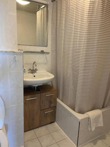 a bathroom with a sink and a shower curtain at Sfeervol en gezellig gelegen appartement op Texel in De Koog