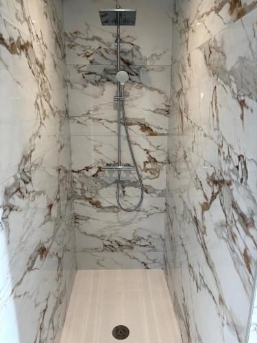 La salle de bains est pourvue d'une douche et de murs en marbre blanc. dans l'établissement Maison neuve 4 chambres, à Cléder