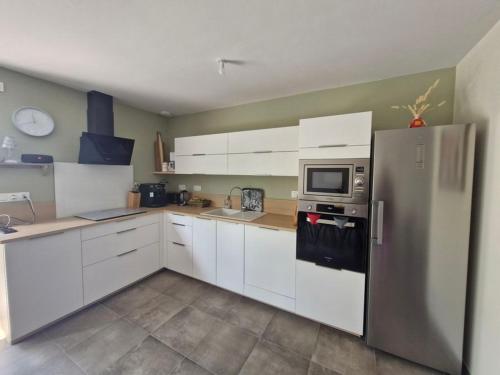une cuisine avec des armoires blanches et un réfrigérateur en acier inoxydable dans l'établissement BELLE MAISON NEUVE FAMILIALE JOLIE VUE DEGAGEE 8 Personnes, à Saint-Jean-de-Monts