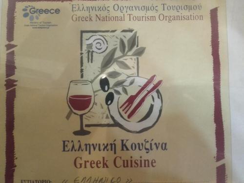 オマロスにあるTo Ellinikonのワインボトルとグラスワインのラベル