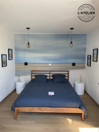 a bedroom with a bed with blue sheets and two tables at L'Atelier in Peuplingues
