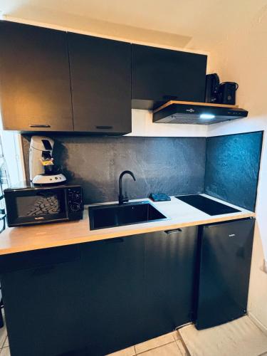La cuisine est équipée de placards noirs, d'un évier et d'un four micro-ondes. dans l'établissement Love Room-Jacuzzy-Beziers, à Béziers