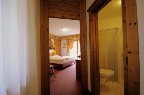 a room with a bathroom with a bed and a sink at Hotel Al Forte in Arabba