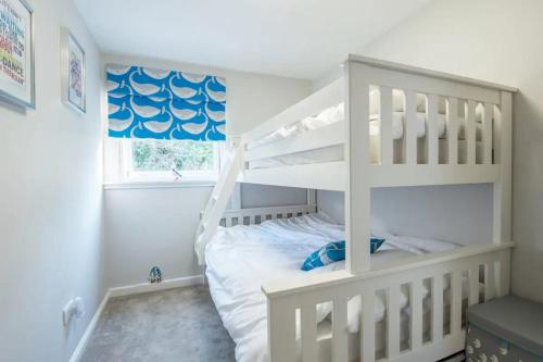 1 dormitorio con litera blanca y ventana en Charming Beach Chalet with Balcony & Sea Views, en Pembrokeshire