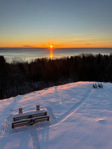 two people skiing down a snow covered slope with the sunset at Horizon 777 in Saint-Siméon