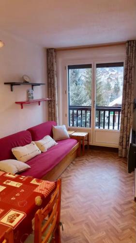 - un salon avec un canapé violet et une grande fenêtre dans l'établissement Serre Chevalier Appart 4 p 1er étage Aiglon Nord, à La Salle Les Alpes