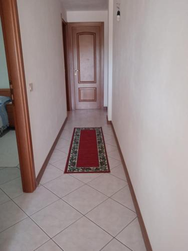 a hallway with a door and a red rug on the floor at Lungomare 2 in Porto Alabe
