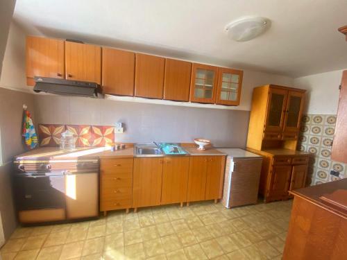 una cucina con mobili in legno, un lavello e una stufa di La Casetta nel Borgo a Mezzana