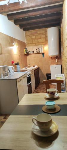 - une cuisine avec une table avec des tasses et des assiettes dans l'établissement Duplex avec cour au coeur de la cité médiévale., à Gourdon