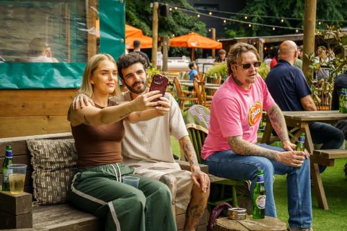 three people sitting on a bench looking at a cell phone at The Drayton Court Hotel in London