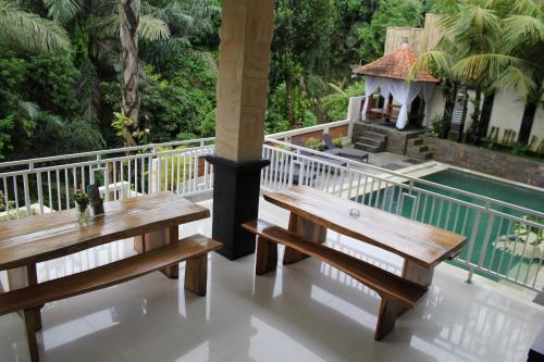 a balcony with two wooden benches and a pool at Hanaka Riverside Ubud in Ubud