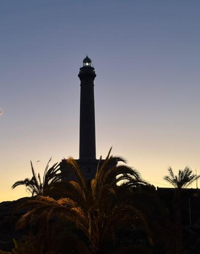 a lighthouse with a palm tree in front of it at Chalet del Faro in Cabo de Palos