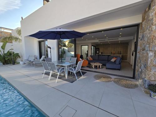 a patio with a table and an umbrella next to a pool at Chalet del Faro in Cabo de Palos