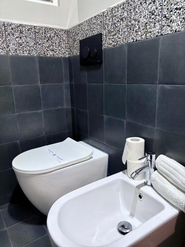 a bathroom with a white toilet and a sink at Favola Guesthouse Affittacamere in Nettuno