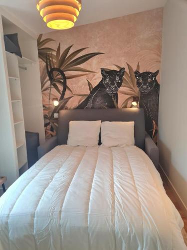- une chambre avec un lit avec deux chats sur le mur dans l'établissement Charmant appartement face au port de Concarneau, à Concarneau