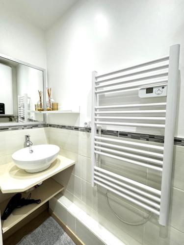 une salle de bain blanche avec un lavabo et un miroir dans l'établissement La Loge Urbaine - Cœur de Ville, à Avignon